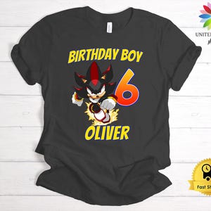 Könnte beinhalten: Schwarzes T-Shirt mit einer Comicfigur und dem Text "Birthday Boy" und "Oliver". Die Zahl 6 ist orange.