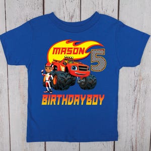 May include: Blue short-sleeved t-shirt with a colorful graphic. The graphic features a red monster truck with the name "MASON" above it, the number "5", and the words "BIRTHDAY BOY". A cartoon character is also included.