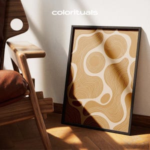 Peut inclure: Une affiche encadrée rectangulaire avec le texte colorituals en haut. L'œuvre présente un motif abstrait de formes organiques fluides dans des tons de beige, de brun clair et de brun foncé, remplies de détails en lignes concentriques fines.