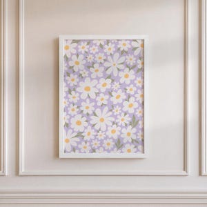 Peut inclure: Une impression d'art murale rectangulaire dans un cadre blanc présentant un motif répétitif de fleurs de marguerites blanches avec des centres jaunes et de petites feuilles vertes sur un fond violet clair uni. L'œuvre est centrée sur un mur.