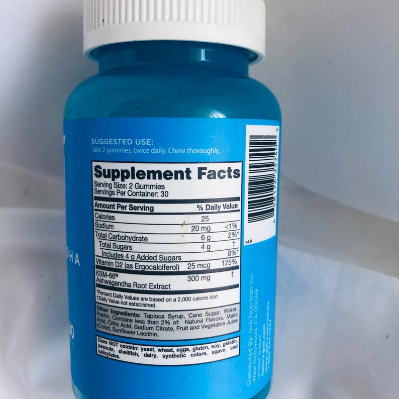 K&ouml;nnte beinhalten: Eine blaue Erg&auml;nzungsflasche mit wei&szlig;em Deckel. Das Etikett zeigt "N&auml;hrwertangaben" und Details zum Produkt, einschlie&szlig;lich Kalorien, Vitaminen und Ashwagandha-Wurzelextrakt. Die Flasche enth&auml;lt 30 Portionen.