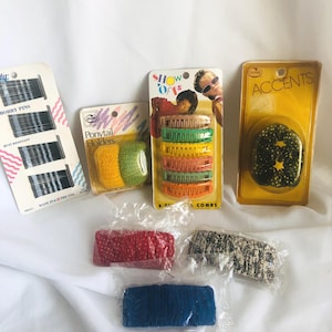 Puede incluir: Surtido de accesorios para el cabello vintage, que incluyen horquillas negras, coleteros amarillos y verdes, peines coloridos y una rosquilla para el cabello. Empaquetado en envases de estilo retro con la marca "Goody".