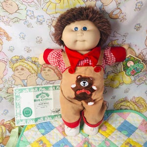 May include: A set of three ceramic mugs with a speckled, matte finish. The mugs are in shades of cream, light brown, and dark brown. Each mug has a simple, minimalist design and a rounded handle.