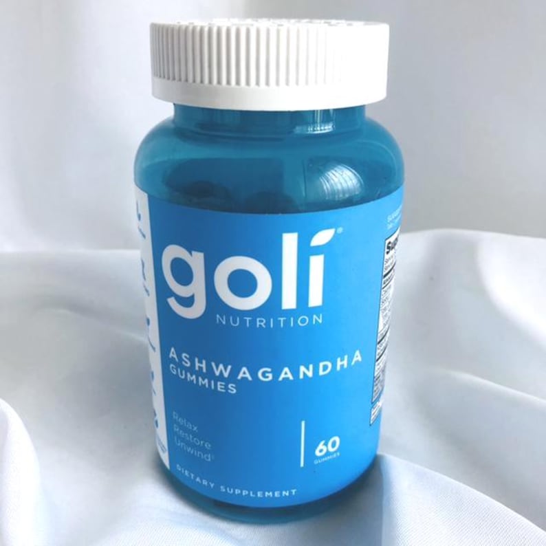 K&ouml;nnte beinhalten: Eine blaue Plastikflasche mit Goli Nutrition Ashwagandha Gummies und einem wei&szlig;en Deckel. Das Etikett zeigt den Markennamen und Produktinformationen, einschlie&szlig;lich "60 Gummies" und die Worte "Relax, Restore, Unwind."