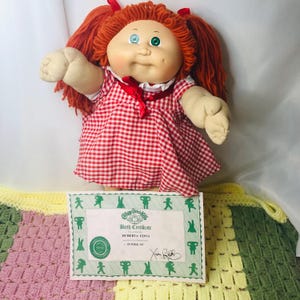Puede incluir: Muñeca vintage Cabbage Patch Kids con pelo de hilo rojo y un vestido a cuadros rojos y blancos. La muñeca tiene un certificado de nacimiento que dice "Huberta Edna". Un artículo de colección.