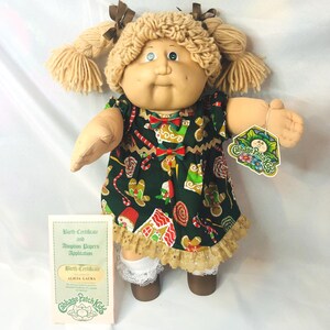 Muñeca Cabbage Patch Kid Coleco HM2 vintage, con pecas, cabello color caramelo y ojos verdes. Incluye papeles de adopción y etiqueta colgante.