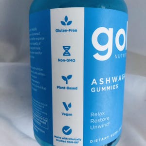 K&ouml;nnte beinhalten: Eine blaue Flasche Ashwagandha-Gummis der Marke "go". Das Etikett weist darauf hin, dass das Produkt glutenfrei, gentechnikfrei, pflanzlich und vegan ist. Der Text auf der Flasche lautet au&szlig;erdem "Relax, Restore, Unwind" und "Nahrungserg&auml;nzungsmittel."