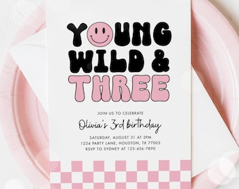 May include: A white invitation card with the text "YOUNG WILD & THREE" in black and pink, with a smiling face icon. The invitation is on a pink plate and includes details for Olivia's 3rd birthday.