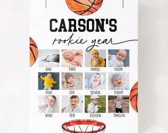 May include: A white poster with a basketball theme, featuring the text "CARSON'S rookie year." It includes a basketball graphic and a grid of twelve baby photos, each labeled with a month number. A basketball hoop graphic is at the bottom.