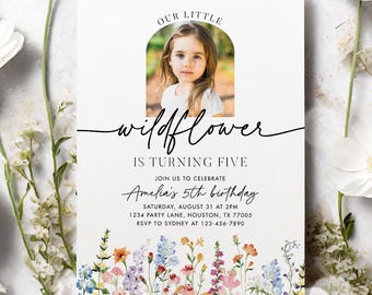 May include: A white invitation card with a photo of a young girl, surrounded by white flowers and greenery. The card reads "Our Little Wildflower is Turning Five" with event details. Floral illustrations decorate the bottom of the card.
