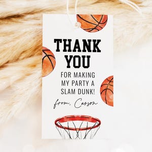 May include: A white gift tag with a basketball theme, featuring the words "THANK YOU" in bold black text. The tag includes basketball illustrations and the text "FOR MAKING MY PARTY A SLAM DUNK!" and "from, Carson".