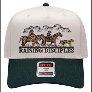 Puede incluir: Gorra de b&eacute;isbol con corona blanca y visera verde oscuro. La gorra presenta una ilustraci&oacute;n de vaqueros a caballo y el texto "RAISING DISCIPLES". La gorra tiene un ajuste cl&aacute;sico y est&aacute; hecha de tela de primera calidad.