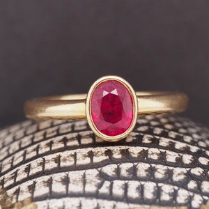 以下が含まれることがあります： 赤い楕円形のルビーがセットされた金の指輪