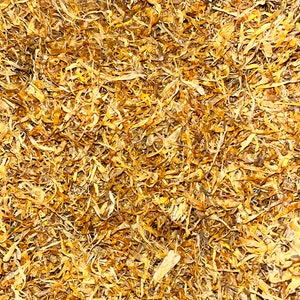 May include: A close-up of a pile of dried, shredded, golden yellow marigold petals.