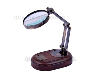 May include: A magnifying glass with a black frame and a wooden base. The magnifying glass is attached to a metal arm that can be adjusted to different angles.