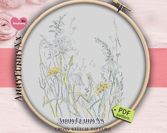 Puede incluir: Un patrón de punto de cruz con flores silvestres, incluyendo dientes de león, en un bastidor de bordado de madera. El diseño utiliza hilos amarillos, verdes y azules sobre un fondo gris claro. El texto "ANNYFUNNYXX CROSS STITCH PATTERN" es visible.