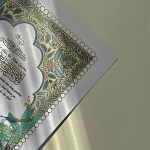 May include: A white background with a decorative border of gold and blue floral designs. The text "Allah, the Most Gracious" is written in Arabic calligraphy in the centre of the image.