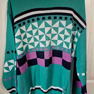 May include: A green, white, black, and purple patterned sweater with the Antigua logo on the front.