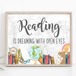 May include: A framed print with the text "Reading is dreaming with open eyes". The print features a globe, books, a compass, glasses, and mountains on a white background with a world map.