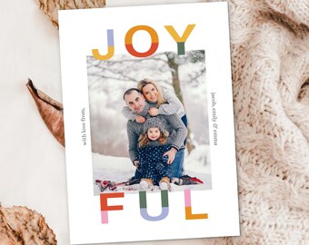 Puede incluir: Una tarjeta navideña blanca con la palabra "JOYFUL" en letras de bloque coloridas. Un retrato familiar está dentro de un borde blanco. La tarjeta incluye el texto "with love from" y "Jacob, Emily & Emma".