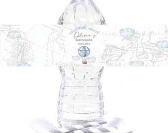 May include: Water bottle label with a vintage map background and a blue hot air balloon. The label says "Adventure Awaits Olivia's Baby Shower 02.01.2023".