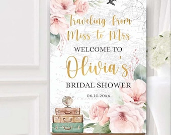 May include: A bridal shower welcome sign with a travel theme. The sign features a watercolor floral design with pink and peach flowers, green leaves, and a vintage world map background. The text reads "Traveling from Miss to Mrs. Welcome to Olivia's Bridal Shower 06.10.20XX".