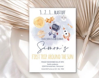 May include: A blue and white astronaut illustration with a rocket and planets on a light blue background. The text reads "3...2...1... BLAST OFF" and "PLEASE JOIN US AS WE CELEBRATE Simon's FIRST TRIP AROUND THE SUN". The invitation includes the date, time, address, and RSVP information.