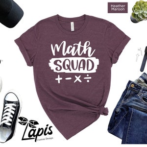 May include: A heather maroon t-shirt with the text "Math Squad + - x :" in white.