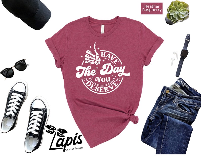 May include: A heather raspberry t-shirt with a white graphic that says "I Have The Day You Deserve" with a thumbs up hand and stars around it.