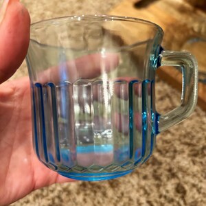 May include: A clear glass mug with a blue rim and vertical lines. The mug has a handle.