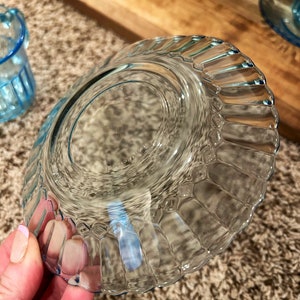 May include: A clear blue glass saucer with a fluted edge. The saucer is empty and has a slight blue tint.