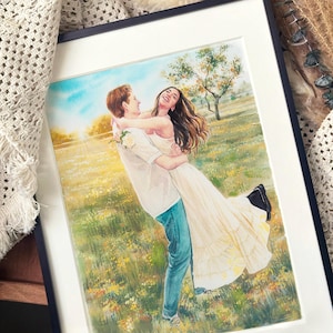 Könnte beinhalten: Aquarellmalerei eines Paares, das sich in einem Feld mit Wildblumen umarmt. Der Mann trägt ein weißes Hemd und blaue Jeans und hebt die Frau in einem cremefarbenen Kleid hoch. Der Hintergrund zeigt einen sonnigen Himmel und Bäume, gerahmt in Schwarz.