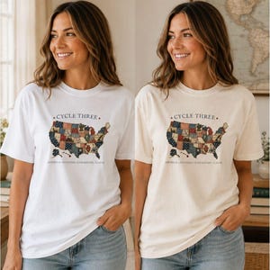 May include: A white and a cream short-sleeve t-shirt, each featuring a graphic of the United States map filled with various patterns. The text "CYCLE THREE" appears above the map, and "AMERICA ANATOMY CHEMISTRY LATIN" is printed below.
