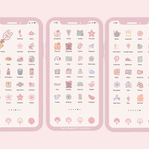 Op de afbeelding: Een roze en wit telefoonscherm met een raster van kleurrijke app-pictogrammen. De pictogrammen zijn gestyled met schattige cartoonfiguren en bloemmotieven. De tekst "THE DEARESTS STUDIO" staat onderaan het scherm.
