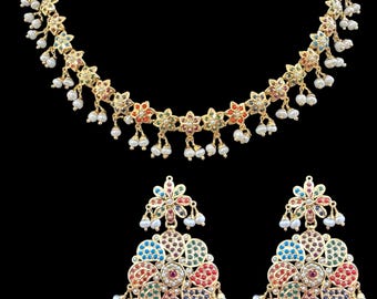 Op de afbeelding: Een goudkleurige sieradenset met een ketting en bijpassende oorbellen. De ketting en oorbellen hebben een bloemenontwerp met kleurrijke edelstenen en kleine witte parels. De set wordt gepresenteerd tegen een zwarte achtergrond.