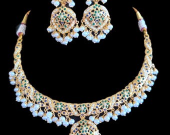 Op de afbeelding: Een gouden ketting en oorbellen set met een bloemmotief, bezet met groene en blauwe edelstenen en witte parels.