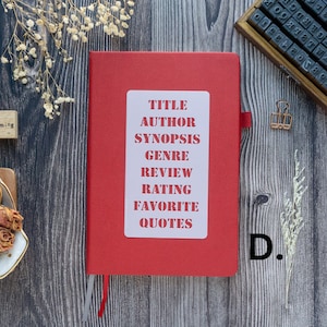 Pode incluir: Um caderno vermelho com um adesivo branco que diz "T&Iacute;TULO, AUTOR, SINOPSE, G&Ecirc;NERO, REVIS&Atilde;O, CLASSIFICA&Ccedil;&Atilde;O, FAVORITO, CITA&Ccedil;&Otilde;ES".