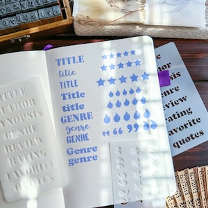Pode incluir: Um est&ecirc;ncil de pl&aacute;stico branco com as palavras "TITLE", "AUTHOR", "SYNOPSIS", "GENRE", "REVIEW", "RATING", "FAVORITE" e "QUOTES" impressas nele. O est&ecirc;ncil est&aacute; em uma p&aacute;gina branca com carimbos de tinta azul das palavras "TITLE", "GENRE", "genre", "GENRE", "genre" e "genre".