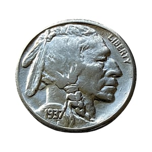 May include: A silver-colored 1937 Buffalo nickel coin featuring a profile portrait of a Native American facing right. The word LIBERTY is inscribed along the upper right edge, and the year 1937 is stamped at the bottom left of the coin face.