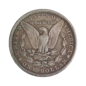 Pu&ograve; includere: Una moneta da un dollaro Morgan color argento raffigurante un'aquila con le ali spiegate che stringe frecce e un ramoscello d'ulivo. Il testo recita UNITED STATES OF AMERICA, IN GOD WE TRUST, ONE DOLLAR, con il marchio CC sotto l'aquila.