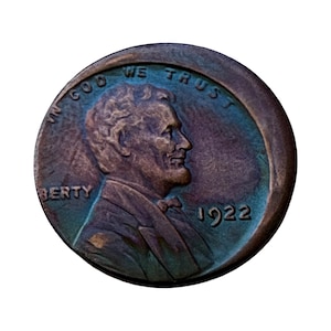 May include: A circular copper-toned United States one-cent coin featuring the profile of Abraham Lincoln facing right. The text IN GOD WE TRUST is arched above the head, the word LIBERTY is on the left, and the year 1922 is printed on the right.
