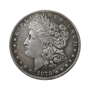 Pu&ograve; includere: Una moneta da un dollaro Morgan color argento del 1878 raffigurante il profilo di Lady Liberty rivolto a sinistra, che indossa un berretto con la scritta LIBERTY, circondata dal testo E PLURIBUS UNUM e tredici stelle lungo il bordo circolare dentellato.