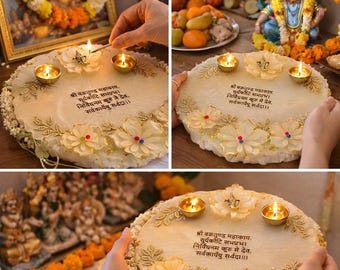 May include: A round, off-white decorative piece with floral and gold leaf accents, holding three lit candles. The piece has text in a script font. The image is part of a religious ceremony, with other religious items in the background.