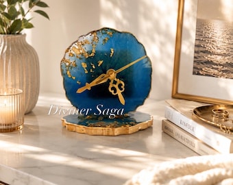 May include: A decorative resin clock with a blue and gold design. The clock face is a deep blue with gold leaf accents, and the hands are gold. The clock sits on a matching base. The text "Diviner Saga" is visible on the clock.