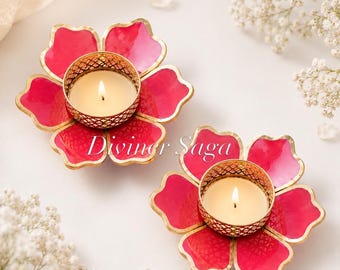 May include: Two flower-shaped candle holders with lit candles. The holders are red with gold trim and a gold filigree cup for the candle. The text "Diviner Saga" is printed on the holders.