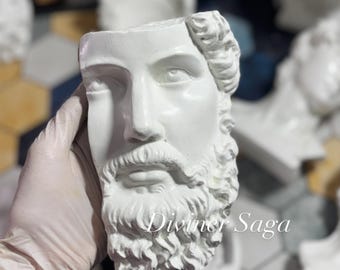 May include: A white plaster bust of a bearded man with detailed facial features. The bust is a planter with an open top. The text "Diviner Saga" is visible on the lower right side of the image. Other busts are visible in the background.