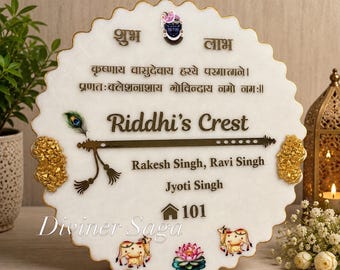May include: A circular white nameplate with scalloped gold edges, featuring the text Riddhi's Crest, Rakesh Singh, Ravi Singh, Jyoti Singh, and 101. It includes a flute graphic, a peacock feather, a lotus, two cows, and Sanskrit text.