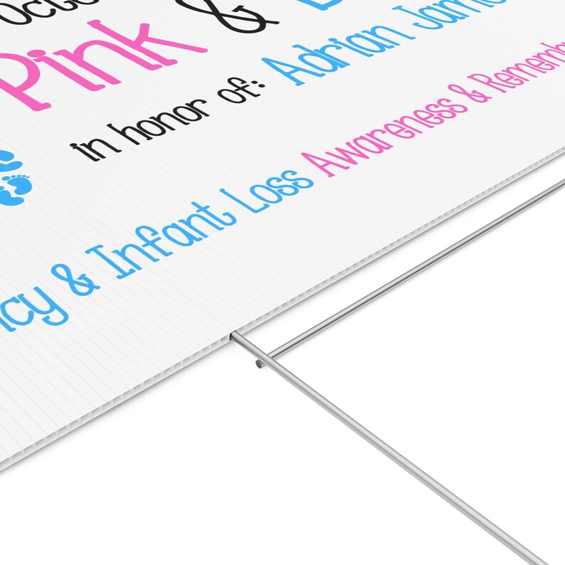 Pode incluir: Placa branca com texto rosa e azul, incluindo as palavras "Pink & Blue" e "Conscientiza&ccedil;&atilde;o e lembran&ccedil;a da perda infantil". A placa &eacute; suportada por uma estaca de metal.