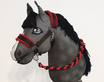 May include: A gray and black stuffed horse head with a red and black bridle and reins. The horse has a black mane and tail.