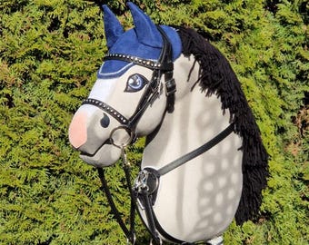 May include: A gray and white horse head with a black mane and tail. The horse is wearing a blue and black bridle with a black leather strap.
